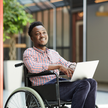 A black person in a wheelchair uses their laptop.